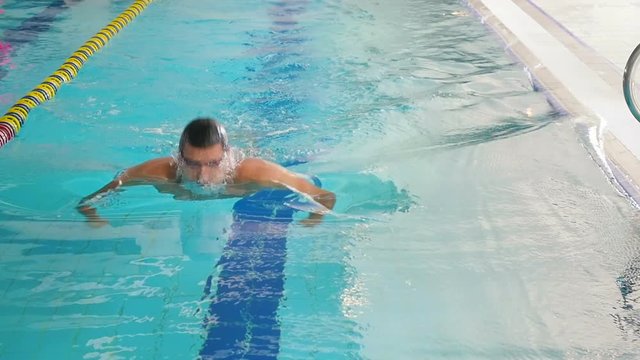 The swimmer swimming under the water in the blue pool