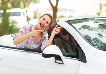 Young woman standing near a convertible with keys in hand