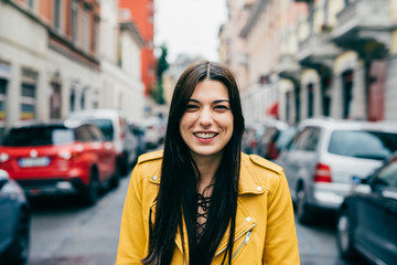Portrait of young beautiful caucasian brown hair woman outdoor in the city looking at camera...