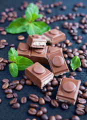 Chocolate, coffee grains and mint on a dark background closeup