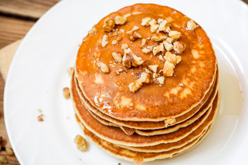 Pancakes with honey and walnuts on rustic wooden background