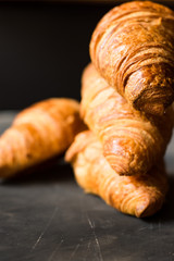 Stack of freshly baked croissants on black background, golden delicious crust,close up,food photography