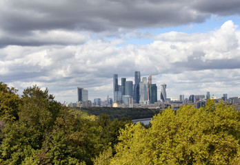 Fototapeta na wymiar View of Moscow financial district and business center from the observation deck at Sparrow hills. Trees, Moskva river and dramatic clouds are in the view.