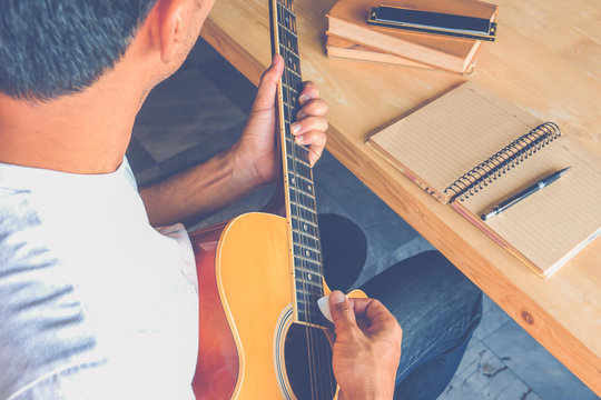 Young man composing the song with guitar on table