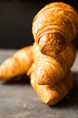 Stack of freshly baked croissants on black background, golden delicious crust,close up