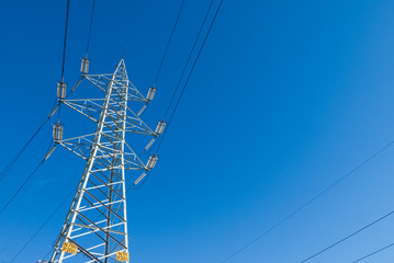 Electric high voltage tower with electric line against clear blue sky