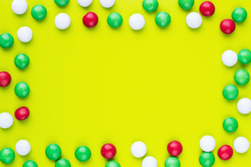 Colored candies in a frame shape on the green background