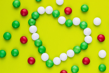 Colored candies in a heart shape on the green background