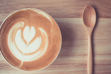 A cup of coffee latte with heart  and wood spoon on table
