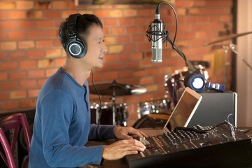 DJ working at radio broadcasting studio,hands adjusting volume and keyboard.
Male radio...