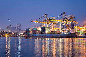 container cargo freight ship with working crane bridge in shipya