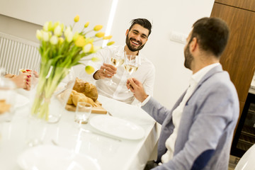 Two young men have dinner and toasting white wine