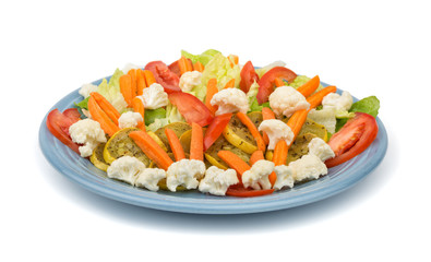 Colorful mixed vegetables with sauteed squash on a light blue plate, on white