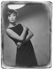 Young girl in evening dresses on grey wall.