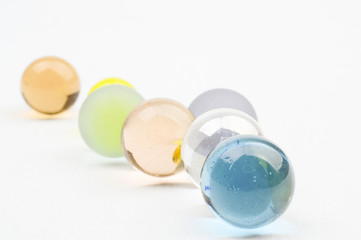 Glass marbles in pastel colors, on white background, diagonally