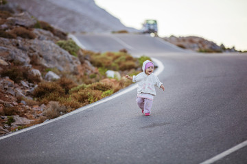 Obraz premium Happy little girl running down road, parents' car parked in distance along road