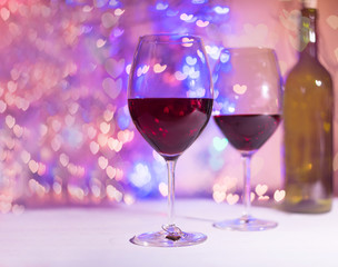 Two glasses with wine with hearts shaped bokeh background. St. Valentines Day