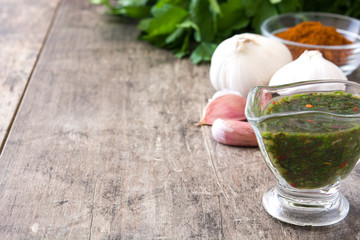 Green Chimichurri Sauce and ingredients on wooden table
