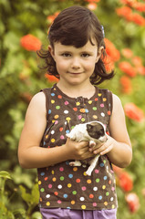 Four years old girl playing with puppy in the garden