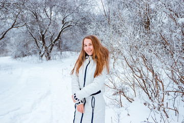 Happy laughing baby in winter forest. Young girl playing in the snow-covered snow park
