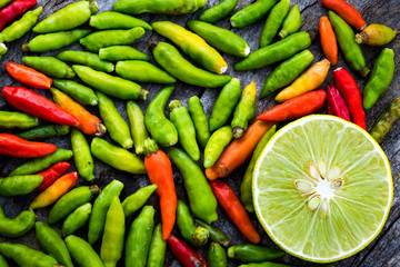 Half lemon on wooden table with red and green chili