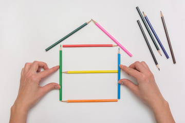 closeup Hands build a house on a piece of paper from the crayons, erecting walls