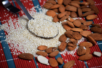 Sesame in a spoon and almonds close-up