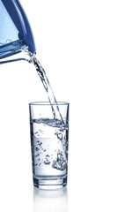 Pouring water from filter pitcher in glass on white background
