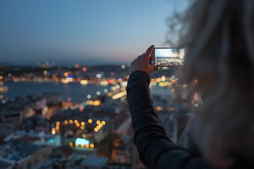 Blonde woman is making photo on her phone of Istanbul from Galata Tower viewing platform