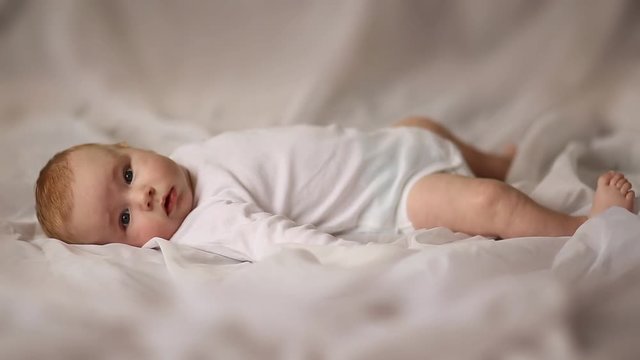 Portrait of four month old baby lying on his back on white cloth