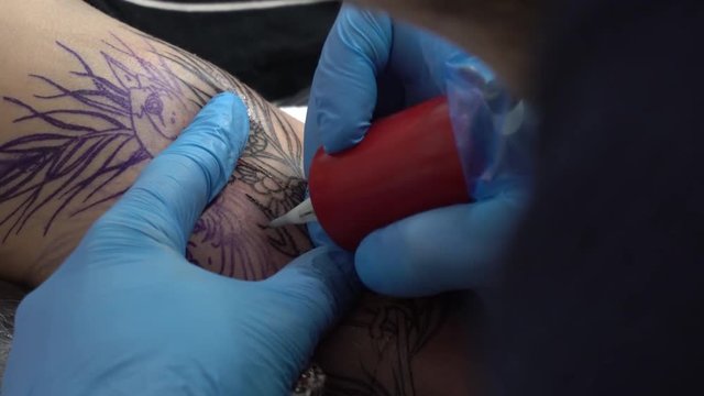 Tattoo master make tattoo on the arm. Tattoo machine close up. Artist tattooing at the workshop. Concept: tattooist, tattooer, freedom, art, young, 4k resolution