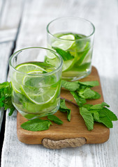 Mojito and ingredients on white wooden surface