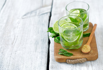 Mojito and ingredients on white wooden surface