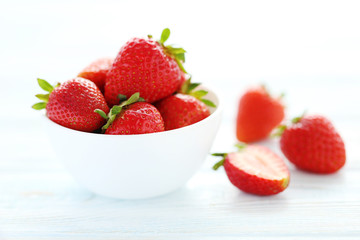 Strawberries in bowl on white wooden table