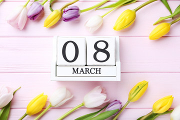 Bouquet of tulips with cube calendar on pink wooden table