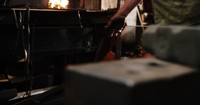 Blacksmith working near fireplace at workshop 4k