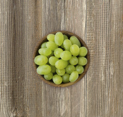 Grapes in a wooden bowl. Green grapes Kish Mish on a wooden background. Top view. Grapes on wooden table with copy space