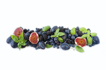 Blue and purple food. Group of fresh fruits and berries with basil's on a white background. Ripe blueberries blackberries grapes plums and figs. Top view with copy space.