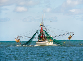 Shrimp trawler fishing boat with nets out on Gulf of Mexico waters by Florida
