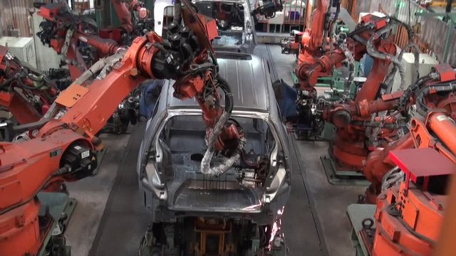 Robots weld car parts in production line at factory