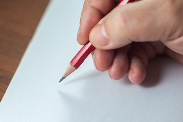 A close photo of a persons writing a letter with a pencil