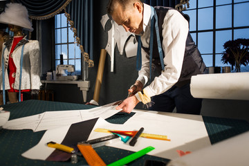 The tailor cuts the pattern sleeves made of paper