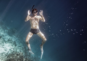 Snorkeling man is posing under the water
