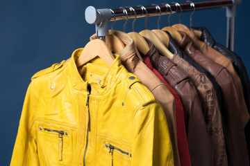 Naklejka premium Different color leather jacket hanging on rack on blue background