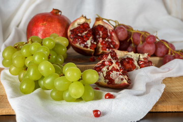 Red and green grapes with pomegranate on a kitchen table