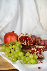 Red and green grapes with pomegranate on a kitchen table
