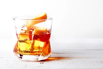 Fotobehang Glass of old fashioned whiskey with ice, orange and cherries over a white wood table © Javier Somoza