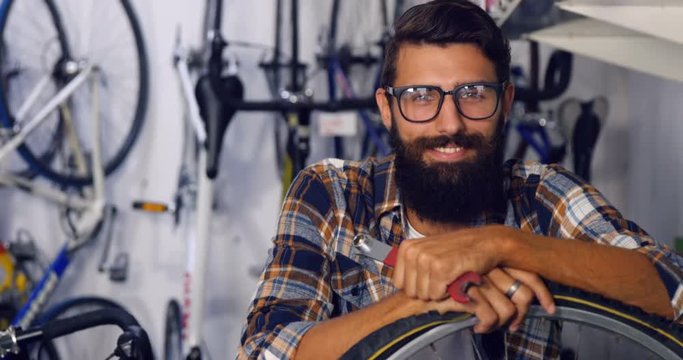 Portrait of smiling mechanic with bicycle in workshop 4k