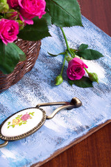 Pink roses in brown basket on blue wooden background.