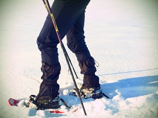 Man legs with snowshoes walk in snow. Detail of winter hike in snowdrift